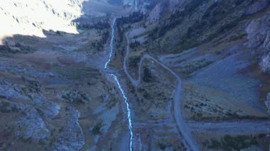 Dağ nehri ve kozalaklı ormanı olan uzun bir vadi. İnsansız hava aracından kayalık uçurumların havadan görünüşü. Yeşil-sarı çimenler yamaçlarda yetişir. Nehir boyunca toprak bir yol var. Kazakistan