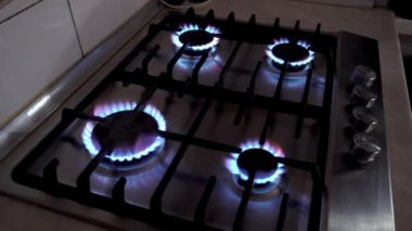 Gaz sobasında mavi bir ateş yanıyor. Benzin evde. Metal gaz sobası. Siyah çubuklar. Kullan-at telefonları aç. Gaz işe yarıyor. Duvarlarda bej fayanslar var. Ekonomik krizi durdurun. Evdeki sıcaklık.