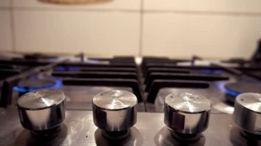 Gaz sobasında mavi bir ateş yanıyor. Benzin evde. Metal gaz sobası. Siyah çubuklar. Kullan-at telefonları aç. Gaz işe yarıyor. Duvarlarda bej fayanslar var. Ekonomik krizi durdurun. Evdeki sıcaklık.