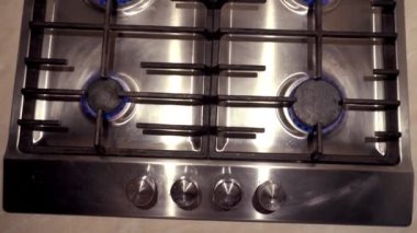 Gaz sobasında mavi bir ateş yanıyor. Benzin evde. Metal gaz sobası. Siyah çubuklar. Kullan-at telefonları aç. Gaz işe yarıyor. Duvarlarda bej fayanslar var. Ekonomik krizi durdurun. Evdeki sıcaklık.
