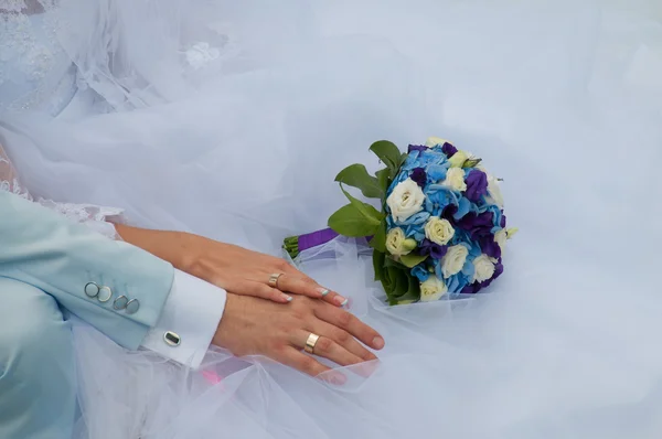 Mãos com anéis de casamento e belo fluxo fresco azul e branco Fotos De Bancos De Imagens