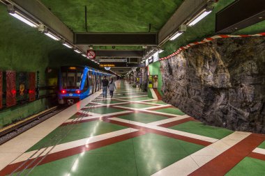 Stockholm, İsveç - 29 Mayıs 2016: Kayadan oyulmuş Kungstradgarden metro istasyonundaki modern tren. Yeşil duvarlar.