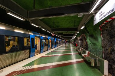 Stockholm, İsveç - 25 Haziran 2016: Kayadan oyulmuş Kungstradgarden metro istasyonundaki modern tren. Yeşil duvarlar.