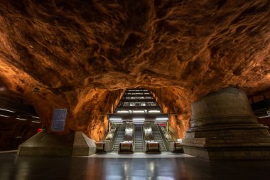 Stockholm, İsveç - 25 Haziran 2016: Radhuset Metro İstasyonu 'nda yürüyen merdiven, kayadan oyulmuş metro istasyonu. Kahverengi duvarlar.