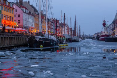 Copenhagen, Denmark - 06 March 2018: Nyhavn in the evening. A 17th-century waterfront, canal and entertainment district with brightly colored townhouses, bars, pubs, restaurants and historical ships.