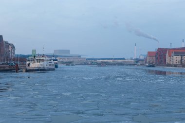 Copenhagen, Denmark - 06 March 2018: View of the industrial part of the city. Smoky, tall chimneys in the background. Winter time. Ice floating in the bay.