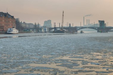 Copenhagen, Denmark - 06 March 2018: View of the industrial part of the city. Smoky, tall chimneys in the background. Winter time. Ice floating in the bay.