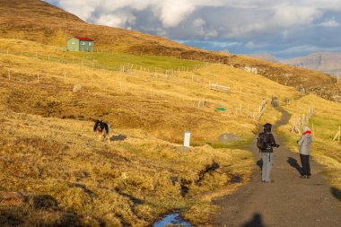 Sandavagur, Faroe Adaları - 28 Nisan 2018: Cadı Parmaklı Turistler. Tepeler var. Güneşli bir bahar akşamı.