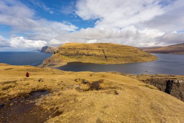 Sandavagur, Vagar, Faroe Adaları- 29 Nisan 2018: yürüyüş yolu üzerinde turistler, turistlerin turba tarlasına giden eski yol, bir Traelanipan Patikası. Köle Uçurumu manzarası. Vagar adasında bulutlu bir gün.
