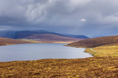 Okyanusun üzerindeki Leitisvatn Gölü manzarası. Yürüme alanı, turba tarlası, Traelanipan Patikası. Vagar adasında bulutlu bir gün. Faroe Adaları.