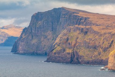 Okyanusun yukarısındaki Leitisvatn Gölü yakınındaki kıyı şeridi manzarası. Yürüme alanı, turba tarlası, Traelanipan Patikası. Vagar adasında bulutlu bir gün. Faroe Adaları.