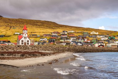 Sandavags Kirkja manzarası, Vagar Adası 'ndaki Sandavagur kilisesi. Bir tepenin yamacında küçük bir köy. Faroe Adaları.