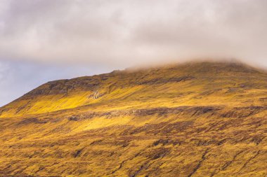 Bulutlarla kaplı dağın manzarası. Dağ manzarası. Vagar Adası 'ndaki Sandavagur. Faroe Adaları.
