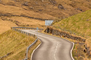 Vagar adasındaki sahil boyunca uzanan yol manzarası. Dağ manzarası. Vagar Adası 'nda bir otobüs. Faroe Adaları.
