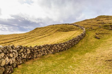 Vagar adasındaki dağ manzarası. Bulutlu bahar günü. Faroe Adaları.