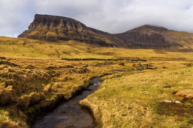 Vagar adasındaki dağ manzarası. Bulutlu bahar günü. Faroe Adaları.