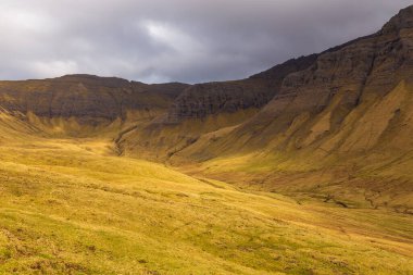 Vagar adasındaki dağ manzarası. Bulutlu bahar günü. Faroe Adaları.