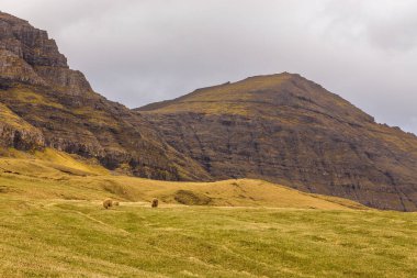 Vagar adasındaki dağ manzarası. Bulutlu bahar günü. Faroe Adaları.