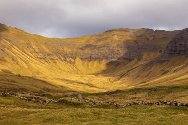 Vagar adasındaki dağ manzarası. Bulutlu bahar günü. Faroe Adaları.
