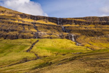 Streymoy Adası 'ndaki dik bir dağ yamacından akan bir şelale volkanik takımadanın bir parçası, Saksun, Faroe Adaları, Danimarka.