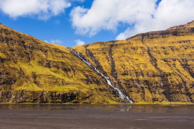 Güzel bir bahar manzarası. Osin Körfezi 'ndeki Pollurin Gölü manzarası ve Faroe Adaları' ndaki dik bir dağ yamacından aşağı akan şelale manzarası. Streymoy Adası, Danimarka, Avrupa 'nın muhteşem manzarası.