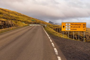 Edi, Faroe Adaları, Danimarka - 03 Mayıs 2018: Streymoy adasındaki tepeler boyunca asfalt yol. İşaret yolu. Vadideki bulutlar
