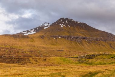 Streymoy adasındaki dağ manzarası. Bulutlu bahar günü. Dağda kar var. Faroe Adaları.