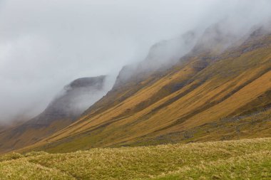 Vagar adasındaki dağ manzarası. Bulutlu bahar günü. Faroe Adaları.