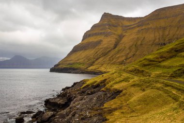 Dik kıyı, Eysturoy adasındaki dağ manzarası. Bulutlu bahar günü. Elduvik, Faroe Adaları, Danimarka.