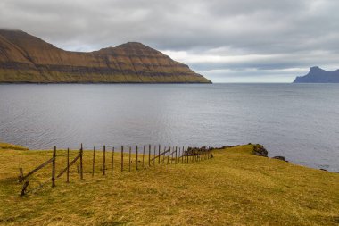 Dik kıyı, Eysturoy adasındaki dağ manzarası. Bulutlu bahar günü. Elduvik, Faroe Adaları, Danimarka.