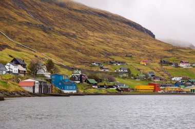 Streymoy adasındaki tepenin yamacında küçük bir liman kasabası. Vestmanna, Faroe Adaları..
