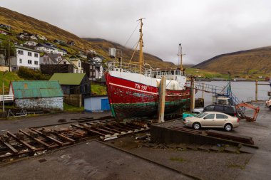 Vestmanna, Faroe Adaları - 05 Mayıs 2018: Kuru bir rıhtıma demirlenmiş eski bir ahşap kesici. Streymoy adasındaki tepenin yamacında küçük bir liman kasabası..
