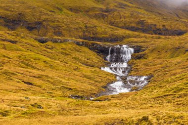 Streymoy adasındaki dağ manzarası. Bulutlu bahar günü. Dağlardan akan şelaleler. Leynar, Faroe Adaları.