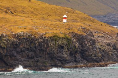 Streymoy Adası 'ndaki Stykkid yakınlarında küçük kırmızı beyaz bir deniz feneri. Faroe Adaları, Danimarka.