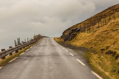 Eysturoy adasındaki sahil boyunca uzanan yol manzarası. Dağ manzarası. Eysturoy Adası 'nda Eidi. Faroe Adaları. Danimarka.