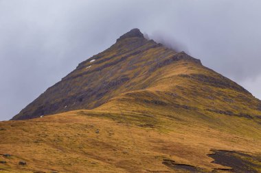 Eysturoy adasındaki dağ manzarası. Bulutlu bahar günü. Dağlardan akan şelaleler. Eğlence Komünü, Faroe Adaları.