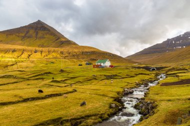 Gjogv, Faroe Adaları, Danimarka - 05 Mayıs 2018: Eysturoy adasındaki dağın yamacında yer alan küçük bir köy. Geleneksel ahşap ev.