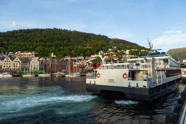 Bergen, Norveç - 27 Mayıs 2018: Bryggen manzarası, Vagen limanının doğu tarafında sıralanan bir dizi Hanseatic mirası ticari binaları. Feribot yolcuları.