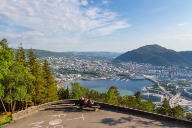 Bergen, Norveç - 28 Mayıs 2018: Floyen Hill 'de bir bankta oturan insanlar. Şehrin görüntüsü ve arka plandaki fiyort.