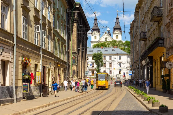 Lviv, Ukrayna - 09 Haziran 2018: Tarihi Lviv kasabasındaki geleneksel binalar. Sarı tramvay durakta..