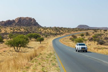 Khomas, Namibya - 28 Eylül 2018: Arabalar yolda. Otoyol boyunca Namibya manzarası. Tepeler ve Afrika bitkileri..