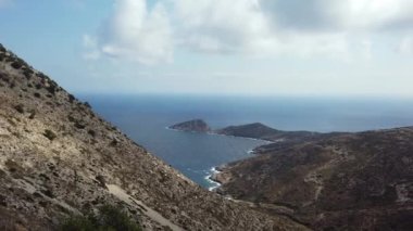 Kıyı şeridi manzarası, dağ manzarası, dolambaçlı yol. Arka planda deniz. Ios Adası, Yunanistan.