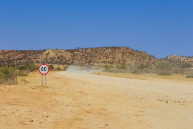 Rehoboth, Namibya - 29 Eylül 2018: Çakıl yolu boyunca Namibya manzarası. Sarı zemin ve Afrika bitkileri.