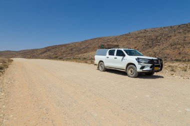 Hardap, Namibya - 29 Eylül 2018: Namibya 'daki tipik 4x4 kiralık araba kamp malzemeleri ve Namibya çölünde toprak bir yolda yol alan bir çatı çadırıyla donatılmış..