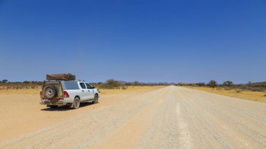 Hardap, Namibya - 29 Eylül 2018: Namibya 'daki tipik 4x4 kiralık araba kamp malzemeleri ve Namibya çölünde toprak bir yolda yol alan bir çatı çadırıyla donatılmış..