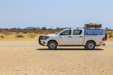 Hardap, Namibya - 29 Eylül 2018: Namibya 'daki tipik 4x4 kiralık araba kamp malzemeleri ve Namibya çölünde toprak bir yolda yol alan bir çatı çadırıyla donatılmış..