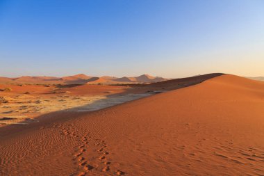 Kum tepesinden Sossusvlei 'nin tuz tepesine inanılmaz bir manzara. Namib Naukluft Ulusal Parkı. Sossusvlei 'deki kum tepeleri. Gün doğumu. Namibya. Afrika.
