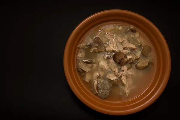 Sopa de cogumelos com cebolas e frango em um fundo preto — Fotografia de Stock