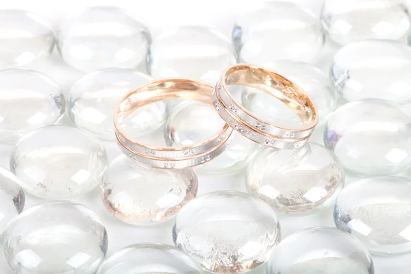 Two gold wedding rings on transparent marbles — Stock Photo, Image