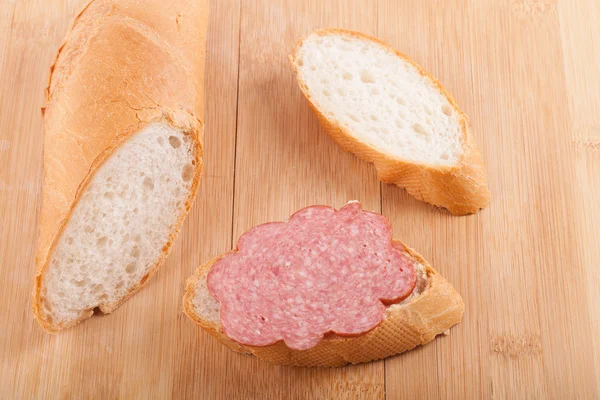 Sandwich with boiled-smoked sausage on wood — Stock Photo, Image
